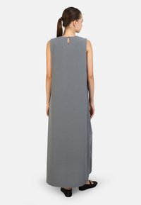 Abito maxi grigio senza maniche con forma dritta, fessure laterali e dettaglio a forma di chiave sul retro. Texture liscia e design alla caviglia.
