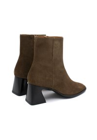 Botas de tobillo de ante marrón con puntera redondeada, tacón de bloque de altura media y cierre de cremallera lateral. Textura suave y diseño sencillo.