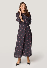 Zwart jurkje met lange mouwen en rode bloemenprint, striknek en stippenstructuur. Draag het met zwarte hoge hakken, en het heeft een comfortabele pasvorm.