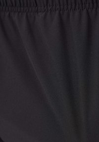 Black fabric, smooth texture, lightweight, gathered waistband detailing, suitable for active wear or casual styling.