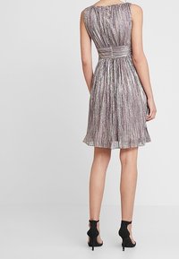 Robe A-line sans manches en tissu métallique avec des plis, dotée d'une taille ajustée et d'une jupe évasée, finition avec une ceinture lisse.