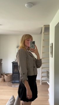 Checkered blazer in black and white with a fitted design; features rolled sleeves and button accents, paired with a flared black skirt.