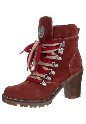 Bottine en daim marron à cheville avec talon épais, lacets rouges et beige, œillets en métal et écusson rond avec logo sur la languette.
