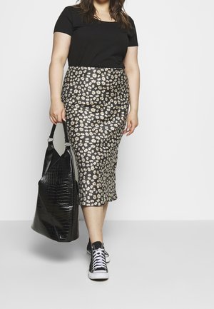 Top nero a maniche corte abbinato a una gonna nera al ginocchio con un motivo floreale. Accessori includono una grande borsa tote nera e sneakers nere.