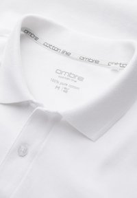 Polo blanc en coton avec col et patte de boutonnage, étiqueté « ombre cotton line », taille M, 100 % coton pur.