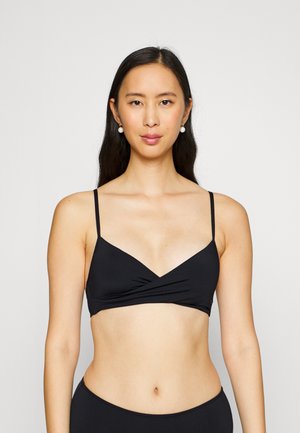 Black bralette with thin adjustable straps, triangular cups, and a twisted front design. Smooth fabric with minimal hardware.