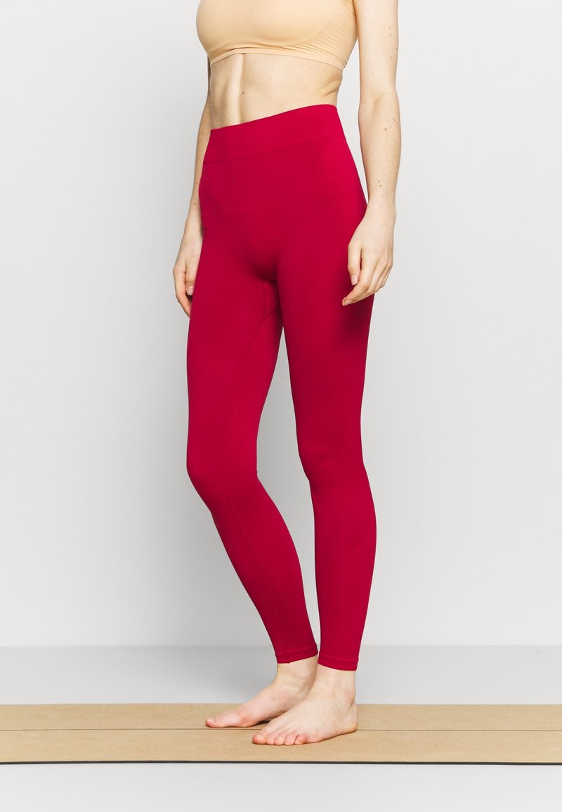 Leggings a vita alta aderenti in tessuto magenta vivace, con texture a coste e design senza cuciture, ideali per l'abbigliamento sportivo.
