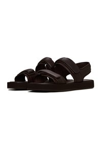 Hnědé kožené sandály s širokými nastavitelnými popruhy, otevřenou špičkou a plochou podrážkou. Mají hladkou texturu a minimalistický styl.