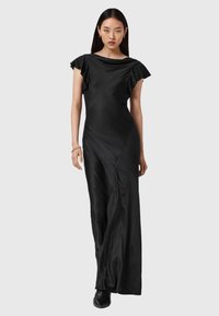 Zwarte satijnen jurk met kapmouwen, elegante drape, asymmetrische onderzoom en minimalistisch ontwerp. Soepele textuur met subtiele glans.