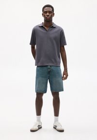 Gray short-sleeve polo shirt with a collar, worn with blue denim shorts. White sneakers with black accents and white socks complete the look.