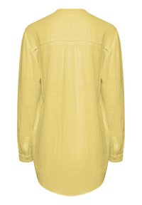 Blusa gialla a maniche lunghe, dal taglio ampio, con maniche con polsini e un dettaglio di cucitura sulla spalla nella parte superiore della schiena.