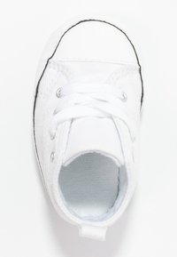 Białe płócienne trampki z czarną gumową podeszwą, okrągłym noskiem i sznurowadłami. Posiadają metalowe oczka oraz gładkie wnętrze.