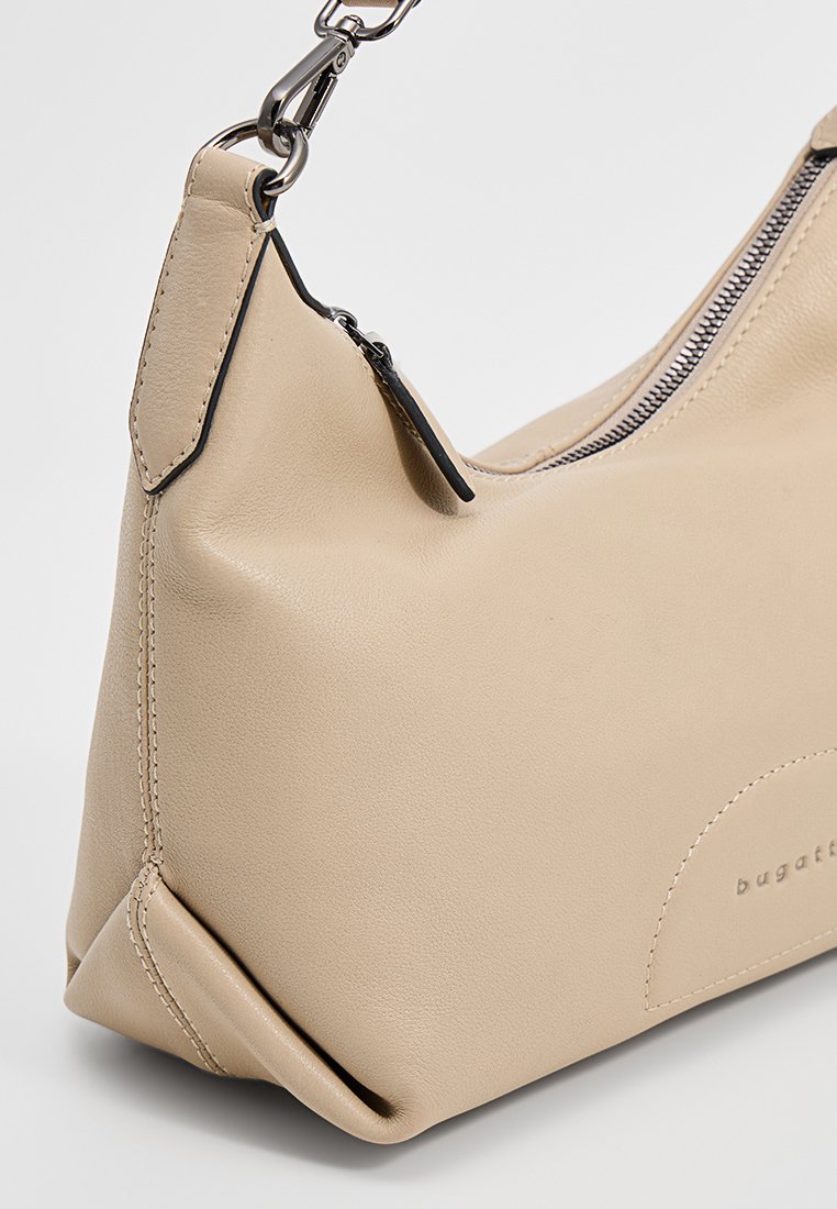 Sac à main en cuir beige avec fermeture éclair noire et fermoir en métal argenté, présentant des coutures détaillées et un léger embossage de la marque.