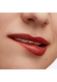 Lebendige rote Lippenfarbe auf glatten, leicht glänzenden Lippen, mit einer natürlichen Hauttextur und subtiler, definierter Kontur.
