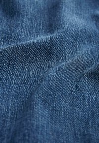 Țesătură din denim de culoare albastru închis, cu textură vizibilă și detalii fine de țesătură. Suprafața pare moale, cu o ușoară strălucire.