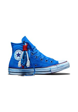 Sneaker Converse alta blu con lacci bianchi, rossi e blu annodati come nappine decorative sul lato, su sfondo bianco.