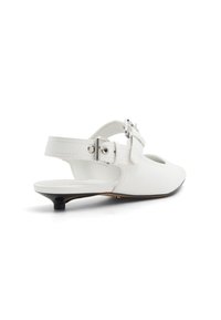 Vit läder slingback-sko med låg klack, utrustad med en justerbar rem och en rund tå. Slät textur och minimalistisk design.