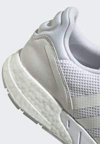 Baltas sporta sneakers ar teksturētu virsmu un sieta akcentiem, mīkstu zoli un elegantām dizaina līnijām. Diskrēta marque uz sāniem.