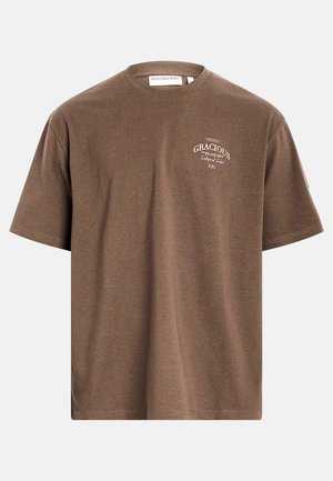 T-shirt marron à manches courtes avec le texte "GRACIOUS Redefined Rebel RBL" en blanc sur la poitrine gauche, présenté sur un fond uni.