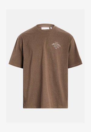 T-shirt marron à manches courtes avec le texte "GRACIOUS Redefined Rebel RBL" en blanc sur la poitrine gauche, présenté sur un fond uni.