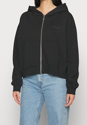 Zwarte cropped zip-up hoodie met een capuchon, frontzakken en ribgebreide manchetten. Gemaakt van zachte stof, met een subtiele logo-detail op de borst.