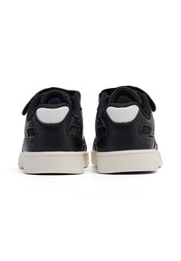 Schwarze Sneaker mit weißen Akzenten, von hinten betrachtet, die ein strukturiertes Lederfinish und Klettverschlüsse zeigen.