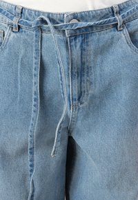 Ανοιχτό μπλε τζιν παντελόνι με κορδόνι στη μέση, κλασικός σχεδιασμός πέντε τσεπών και ήπια ξεθωριασμένη υφή.