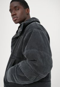 Hall tõmblukk ja kapuutsiga halli kana, millel on mugav lõige, silmapaistvad õmblused ja ees taskud. Tekstureeritud kangas ja struktureeritud õlavarred.