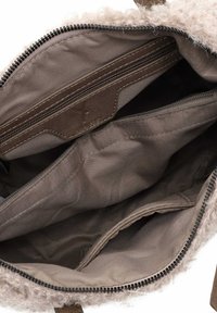 Interno di borsa beige e testurizzato con una tasca con zip e due scomparti aperti, caratterizzato da tessuto liscio e dettagli di cucitura.