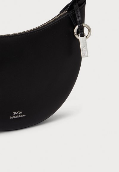 Czarna skórzana torba na ramię w kształcie półksiężyca, z srebrnym okuciem i detalem z logo u dołu. Posiada zamknięcie na zamek.