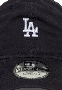 Svart bomullsbasker med justerbar stropp, med hvitt brodert "LA"-logo og New Era 9TWENTY klistremerke på skjermen.
