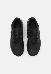 Zapatillas deportivas negras con un patrón texturizado en forma de panal en la parte superior, con un cuello acolchado y diseño con cordones, descansando de forma plana.