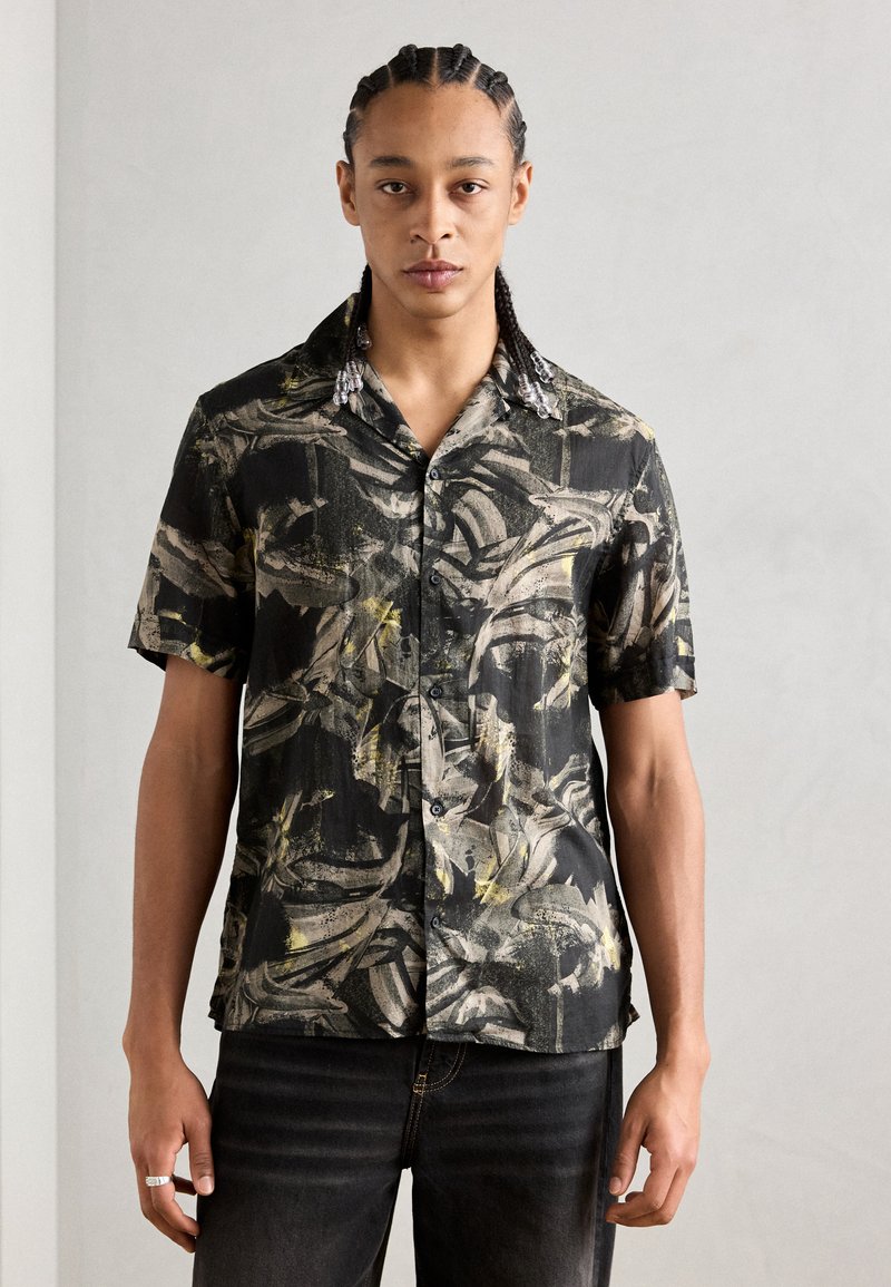Camicia a maniche corte nera con un motivo astratto giallo e grigio. Presenta un'apertura con bottoni davanti e un colletto con accessori decorativi.