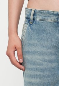 Lichtblauwe denim jeans met een hoge taille, voorzien van een klassiek vijf-pocketdesign, zichtbare stiksels en een licht vervaagde textuur.