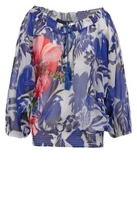 Blouse transparente à motif floral bleu et blanc, avec une grande fleur rose sur le côté gauche, encolure, poignets et ourlet élastiques, et un cordon à pompons bleu.