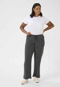 Gray, textured wide-leg pants with a drawstring waist and pockets, paired with a plain white t-shirt and white sneakers.