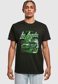 Čierne bavlnené tričko s grafikou v zelenej farbe, na ktorej je napísané "Los Angeles Drift Race", zobrazuje športové auto, plamene a text "10 mph".