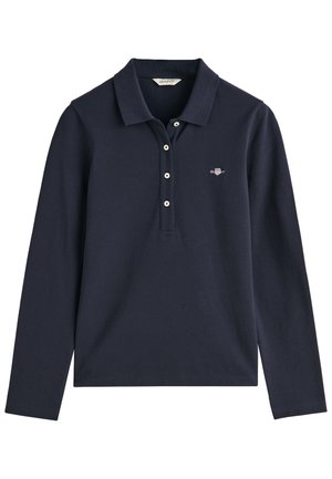 Tamsiai mėlynas polo marškinėliai su ilgomis rankovėmis, apykakle, trijų mygtukų užsegimu ir išsiuvinėtu logotipu kairėje krūtinės pusėje. Medžiaga atrodo lygi.