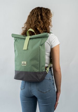 Zelený rolovací batoh s šedým dnem, vyrobený z odolné tkaniny. Obsahuje horní madlo a nastavitelné popruhy, jednoduchý design s logem značky.