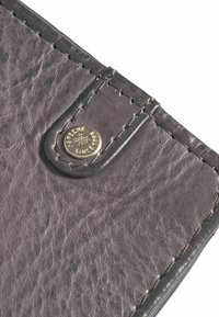 Tmavošedá kožená peňaženka s textúrovaným povrchom, čiernym prešívaním a okrúlym zlatým logom. Zaoblené hrany a elegantný dizajn.