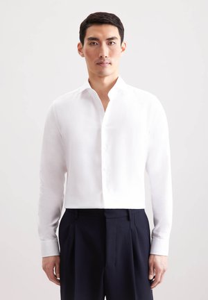 Weißes, knöpfbares Hemd mit Mandarin-Kragen, langen Ärmeln und cropped Design. Verfügt über eine glatte Stoffstruktur und eine taillierte Passform.