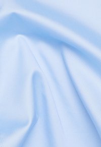 Tessuto azzurro chiaro con una texture liscia, che mostra delicate pieghe e una morbida lucentezza. Il materiale sembra leggero e flessibile.