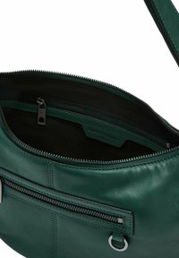 Borsa a mano in pelle verde con un compartimento principale con cerniera e una tasca frontale aggiuntiva. L'interno presenta una fodera nera e un'etichetta con il marchio.