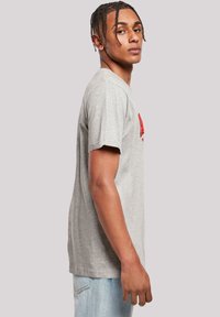 Gray cotton t-shirt with short sleeves, featuring a red logo print on the chest. The fabric appears soft with a casual fit.