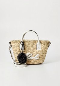 Austa šiaudų rankinė su baltais odos akcentais, kurioje parašytas vardas „Karl“ rašysena ir prisegama juoda gėlės detalė.