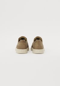 Brune suedette lavtopp sneakers med en teksturert gummisåle, rund tå og elastiske detaljer på hælen for enkel påkledning.
