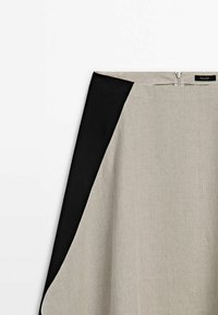 Linnen rok met een zwart zijpaneel en een lichtbeige hoofddesign. Beschikt over een discrete rits aan de achterkant en een gladde textuur.