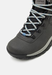 Gray hiking boot with textured synthetic upper, mesh vents, blue and light gray laces, reinforced toe cap, and rubber outsole for traction.