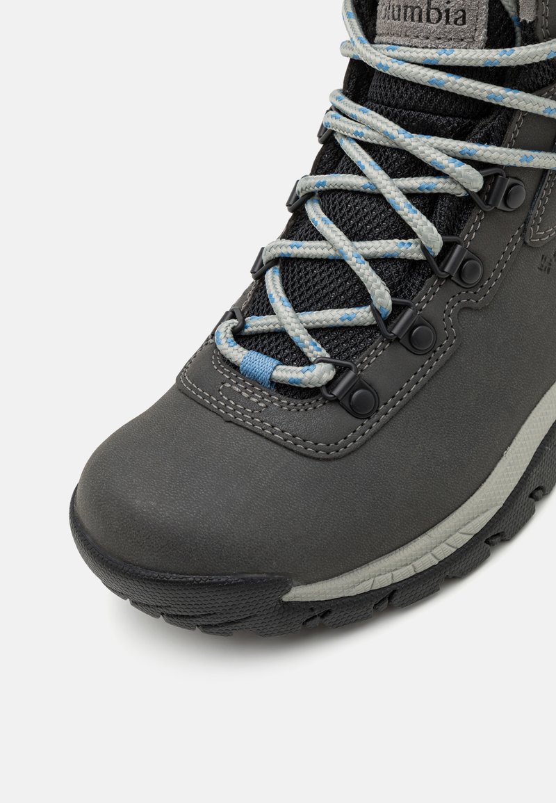 Szare buty trekkingowe z teksturowanym syntetycznym upperem, siateczkowymi wentylacjami, niebieskimi i jasnoszarymi sznurówkami, wzmocnionym noskiem i gumową podeszwą dla lepszej przyczepności.