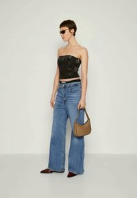 Črn usnjen top brez naramnic, modri široki jeans, rjav ročni torbica in rdeče špicače, dopolnjeno s temnimi sončnimi očali.